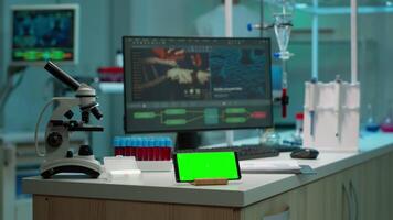 scienziato in piedi a tenere sotto controllo nel sfondo analizzando virus Evoluzione mentre Telefono con modello verde schermo Lavorando nel davanti. donna laboratorio ricercatore l'esame vaccino in via di sviluppo portando sangue campioni video