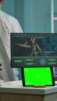 Vertical . Tablet with green screen working in labooratory with mock up, chroma key display while professional engineer testing virus evolution in background. High tech development lab with blood samples video