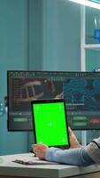 Vertical . Female chemist scientist using green mock-up screen tablet sitting at desk. In background technology research, development laboratory with specialist doctor working in high tech design video