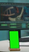 Vertical . Display phone with green screen, mock up on template placed on desk in scientific lab while team of medical researcher scientists analysing virus evolution at digital monitor conducting experiment video