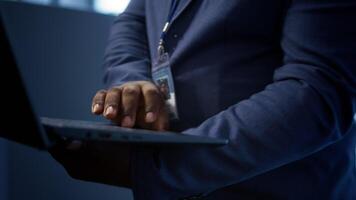 IT technician working on notebook in data center, overseeing server operations. Extreme close up shot of man ensuring optimal performance and data integrity in server hub, camera B video