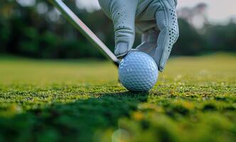 A Gloved Hand Holding A Red Golf Ball Near A Red Tee On A Green Grass Course photo
