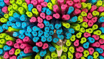 Abstract background of multicolored caps of plastic pens. A set of several liners, markers and colored markers of different colors, top view. photo