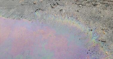 A large rainbow puddle of spilled petroleum product on the road. The concept of environmental pollution photo