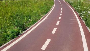 A red synthetic treadmill or bicycle path with white markings, with a turn photo