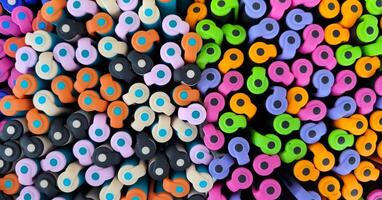 Abstract background of multicolored caps of plastic pens. A set of several liners, markers and colored markers of different colors, top view photo