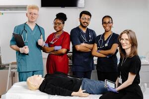 A group of five medical students stand around a training dummy, practicing CPR in a medical training facility photo