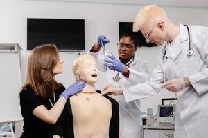 Three medical students practice intubation on a mannequin in a classroom setting photo