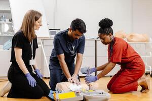 Three medical professionals are practicing CPR on a training dummy, demonstrating proper techniques and procedures photo