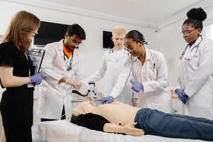 A group of five medical students stand around a training dummy, practicing CPR in a medical training facility photo