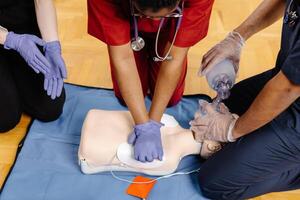 Three medical professionals are practicing CPR on a training dummy, demonstrating proper techniques and procedures photo