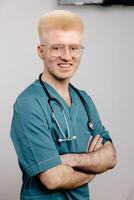 A male doctor in a teal scrub top and stethoscope smiles for the camera photo