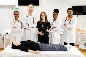 A group of five medical students stand around a training dummy, practicing CPR in a medical training facility photo