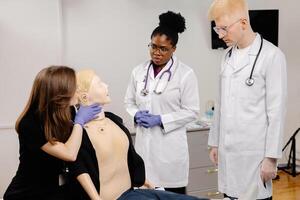 Three medical students practice intubation on a mannequin in a classroom setting photo