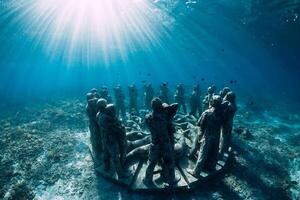 Underwater statues in blue ocean with fish. Underwater tourism in ocean. photo