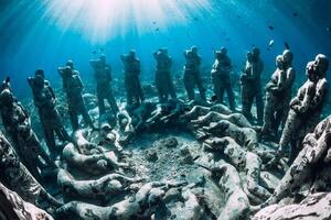 Underwater statues in blue ocean with fish. Underwater tourism in ocean. photo
