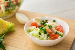 fresh vegetable salad, cabbage, tomatoes in a bowl on a wooden table photo