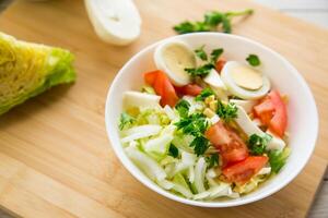 fresh vegetable salad, cabbage, tomatoes in a bowl on a wooden table photo