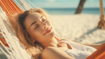 Relaxed young woman reclining comfortably on a hammock at the beach, eyes closed, enjoying a quiet rest with a soft breeze. photo