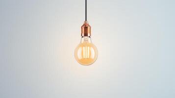 A single incandescent light bulb hangs from a cord against a pale gray background. photo