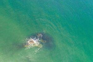 view of a rock on the shore of a beach at low tide, overhead aerial view with drone photo