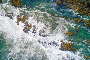waves breaking on the rocks of the coast, aerial top view from a drone. photo