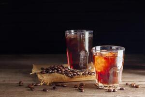 Soft iced coffee with milk, cream, white foam and ice. Coffee latte, espresso, cappuccino, cocktail ready to drink on dark and black background. photo