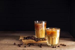 Soft iced coffee with milk, cream, white foam and ice. Coffee latte, espresso, cappuccino, cocktail ready to drink on dark and black background. photo