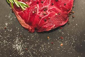 Fresh piece of meat large beef steak on the bone ossobuco with pepper on a black background photo