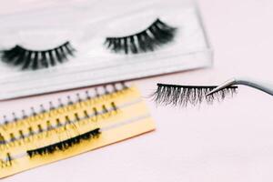 Artificial false fluffy eyelashes with tweezers. photo