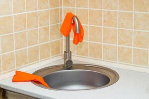 Kitchen sink with faucet and gloves for cleaning. photo