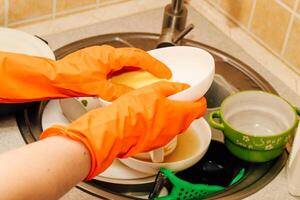A pile of dirty dishes, cups, plates in the sink, washing with an eraser. photo