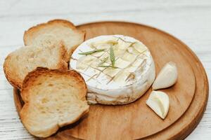 White baguette cut into pieces with olive oil and Camembert cheese on the table. photo