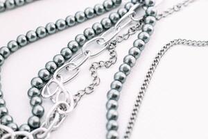 A necklace of gray beads with chain decorations on a white aesthetic background. photo