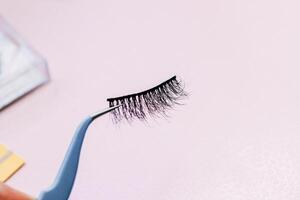 Artificial false fluffy eyelashes with tweezers. photo