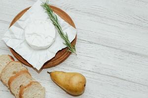 Camembert cheese with pear and rosemary sprig on the table. photo