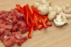 Sliced meat, champignons and red pepper on a board. photo
