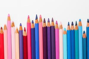 Multi-colored pencils lie on a white table, the violet range of colors photo