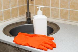Kitchen sink with faucet and gloves for cleaning and detergent photo