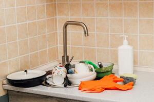 A pile of dirty dishes, cups, plates in the sink. photo