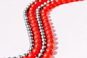 A necklace of red and gray beads on a white aesthetic background. photo