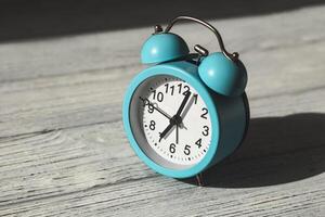 Blue alarm clock on a wooden table, time concept photo
