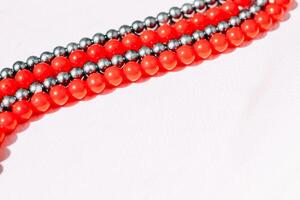 A necklace of red and gray beads on a white aesthetic background. photo