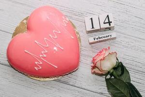Pink tea rose with heart shaped pink mousse cake and February 14 calendar. photo