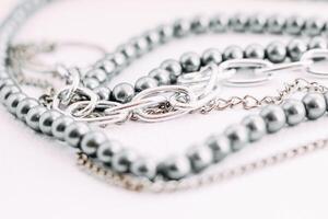 A necklace of gray beads with chain decorations on a white aesthetic background. photo