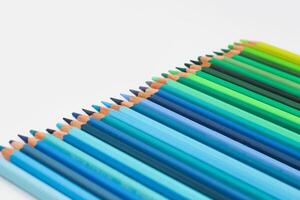 Multi-colored pencils lie on a white table, the green range of colors photo