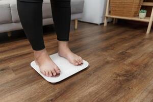Fat diet and scale feet standing on electronic scales for weight control. Measurement instrument in kilogram for a diet control. photo
