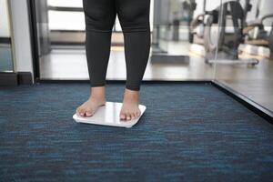 Fat diet and scale feet standing on electronic scales for weight control. Measurement instrument in kilogram for a diet control. photo