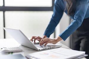 Working by using a laptop computer on wooden table. Hands typing on a keyboard.technology e-commerce concept photo