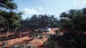 glass greenhouse tower in the middle of a serene field surrounded by lush trees photo